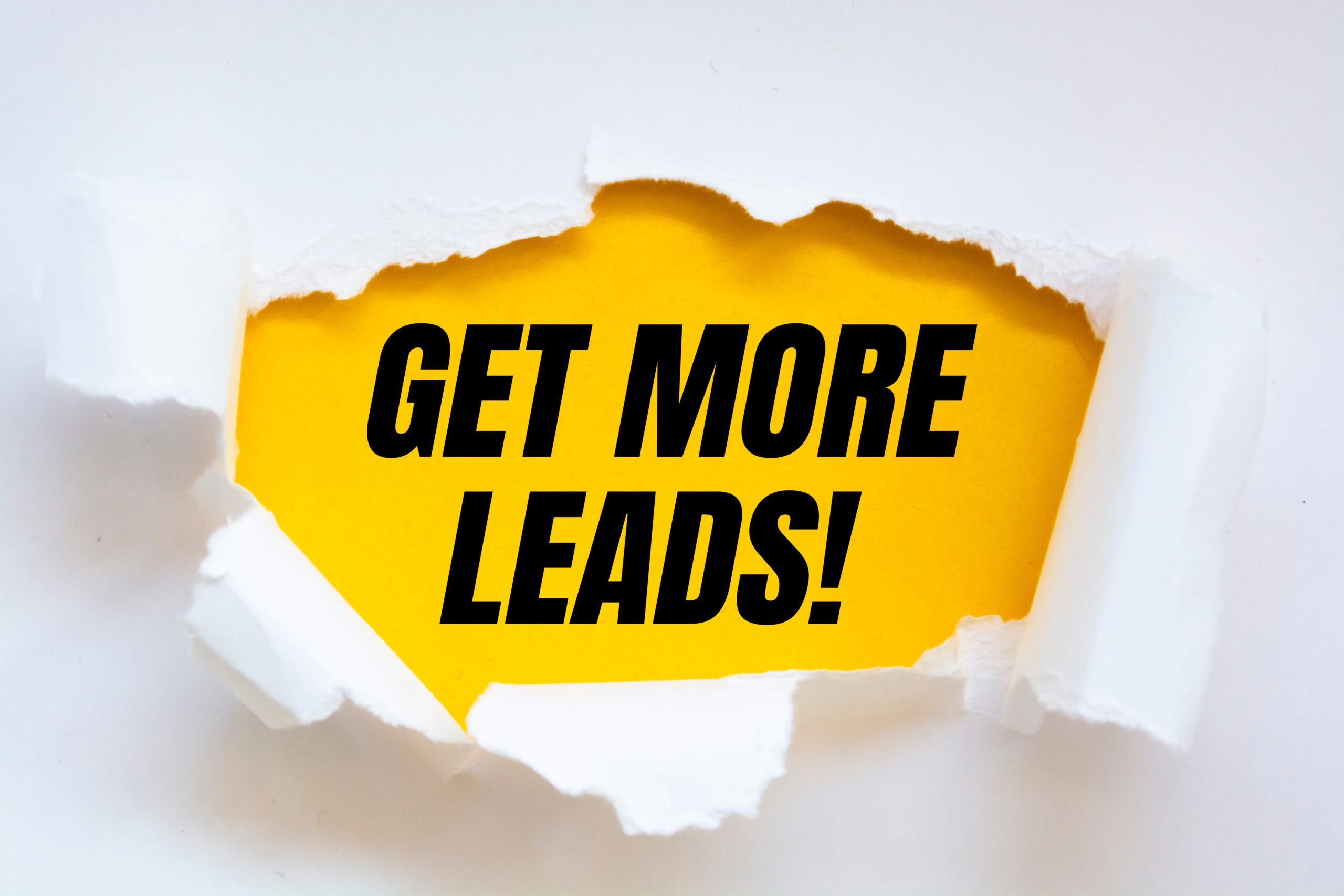 A torn piece of paper revealing the words Get More Leads!